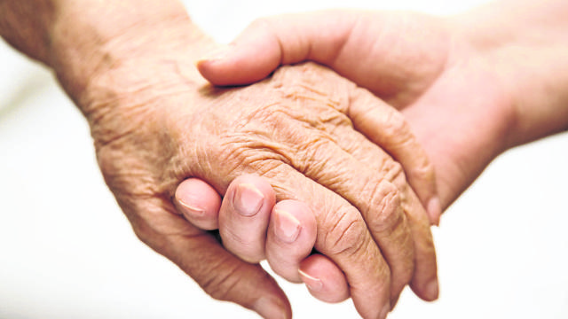 Adult Helping Senior In Hospital